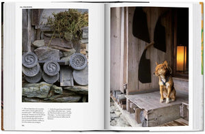 Open book showing traditional Japanese architecture with carved stone and wooden elements, accompanied by a dog on a wooden porch.